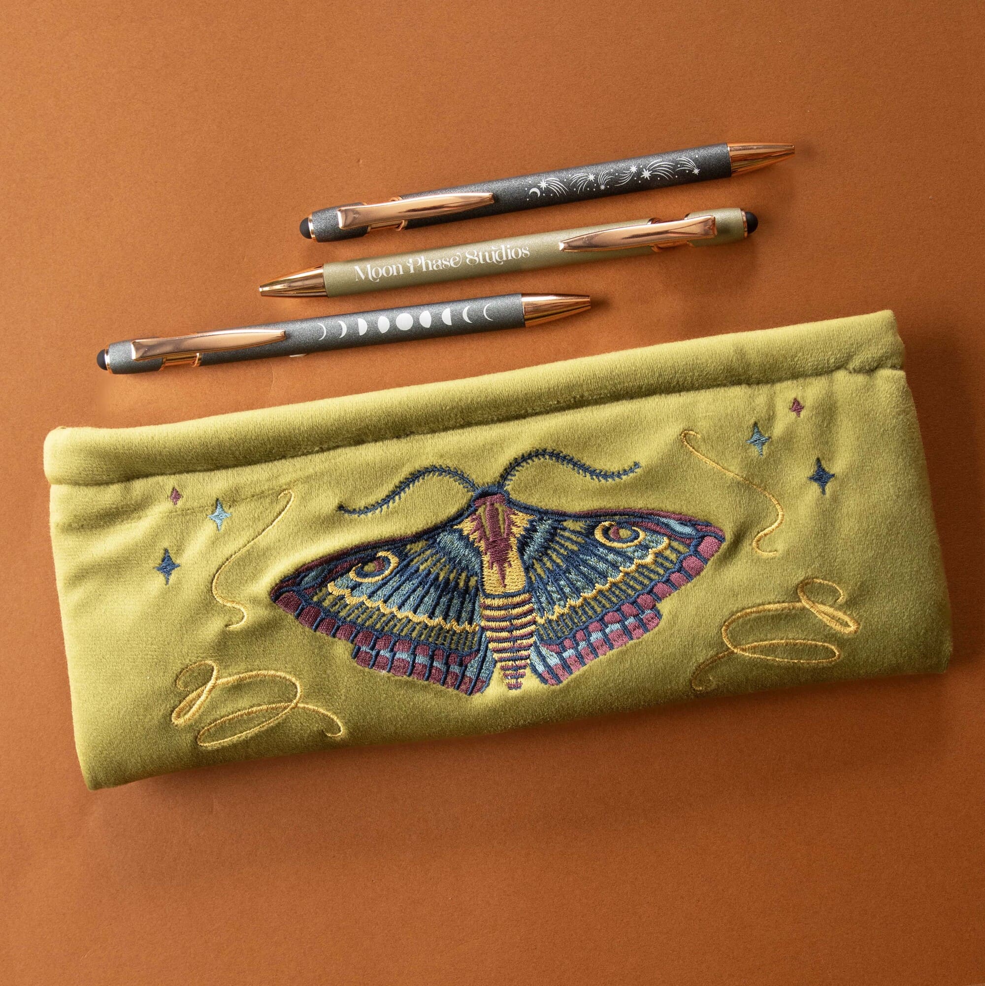 Embroidered pencil case with moth design on a brown background