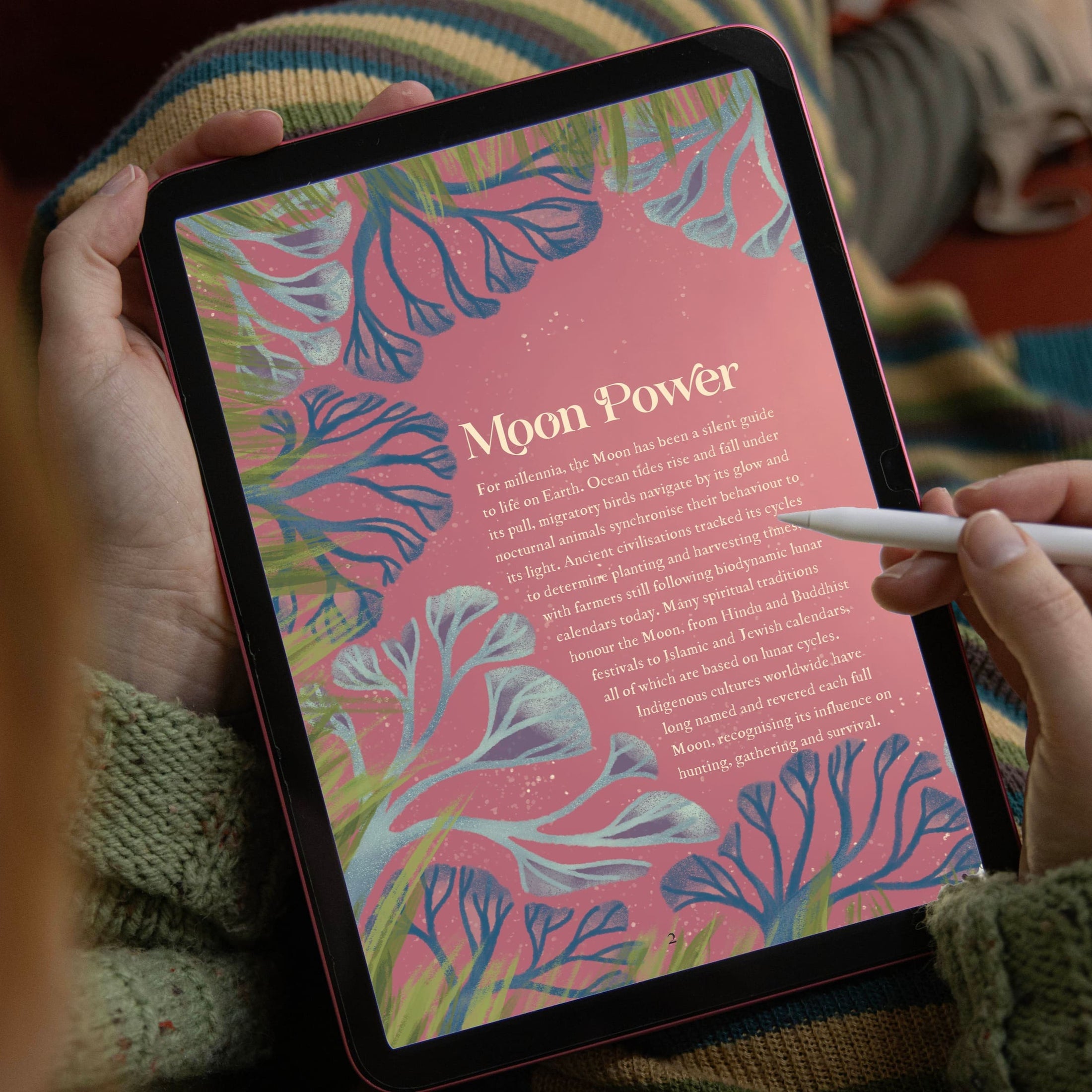 Person holding a tablet with a colorful 'Moon Power' design on the screen.