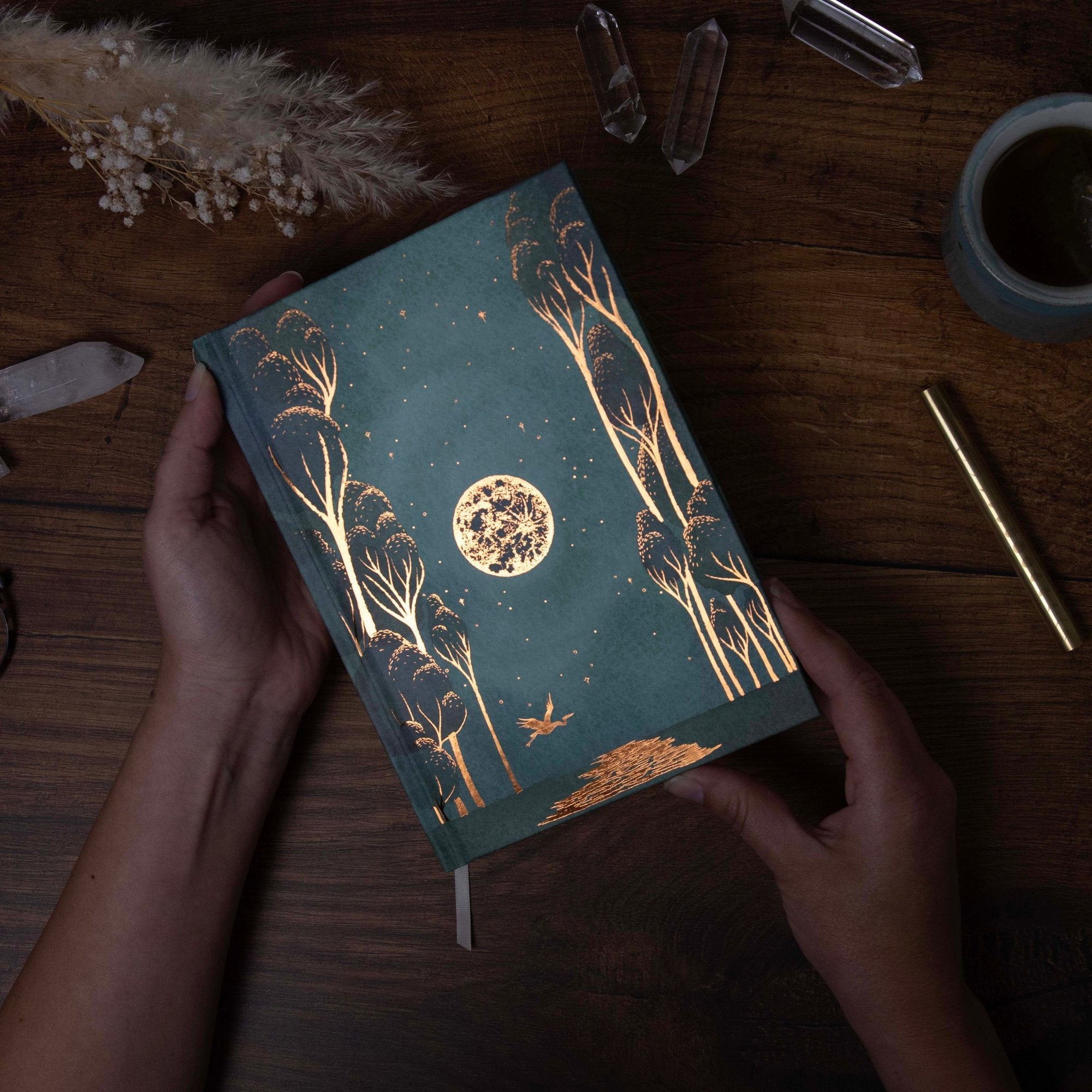 a desk with 13 moon journal 2025 being held with crystals and pen 