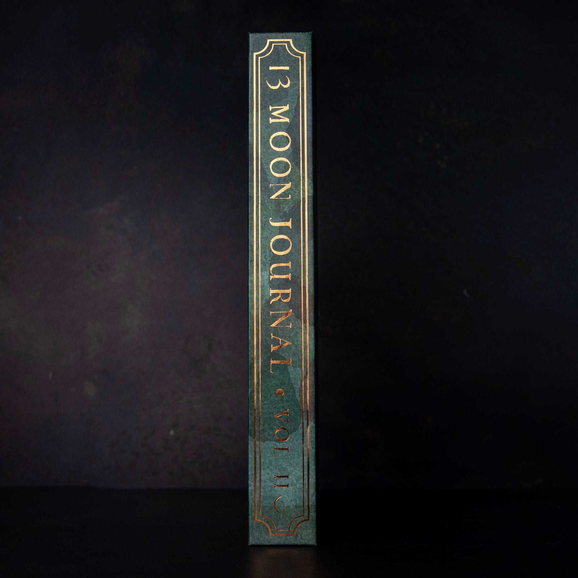 the spine of the 13 moon journal 2025 in green and with gold text and boarder