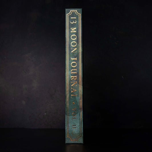 the spine of the 13 moon journal 2025 in green and with gold text and boarder